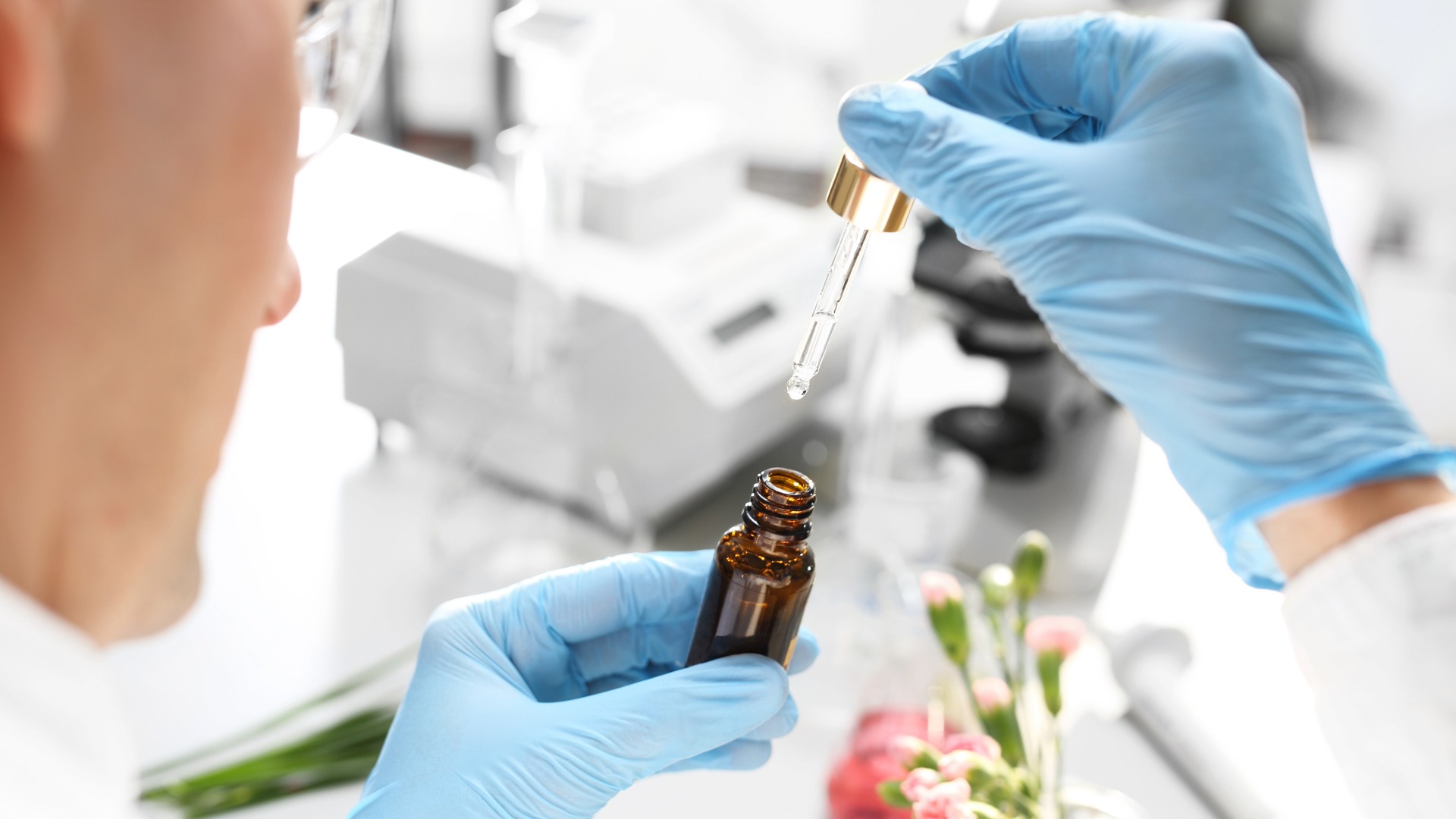 Ein Mann mit blauen Handschuhen öffnet ein braunes Fläschchen mit Serum